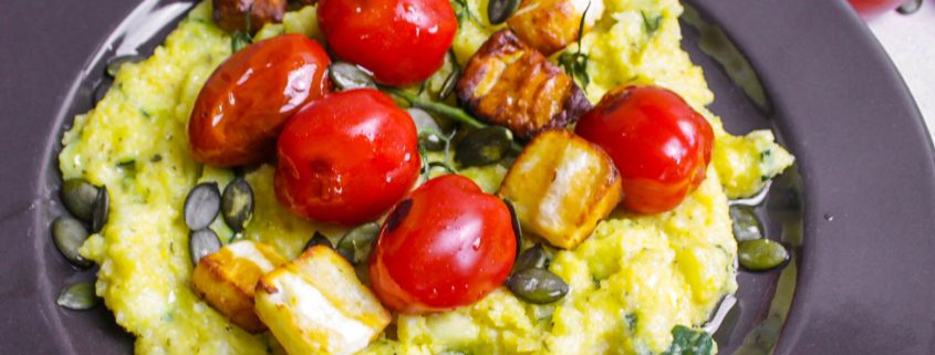 Teller mit Cremepolenta darauf Halloumi Würfel und Cocktailtomaten