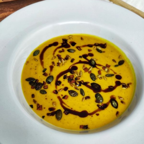 vegane Kürbissuppe mit Orange: Suppeneinlage sind knusprige Speckwüfel, Kürbiskerne und Sonnenblumenkerne sowie Kürbiskernöl